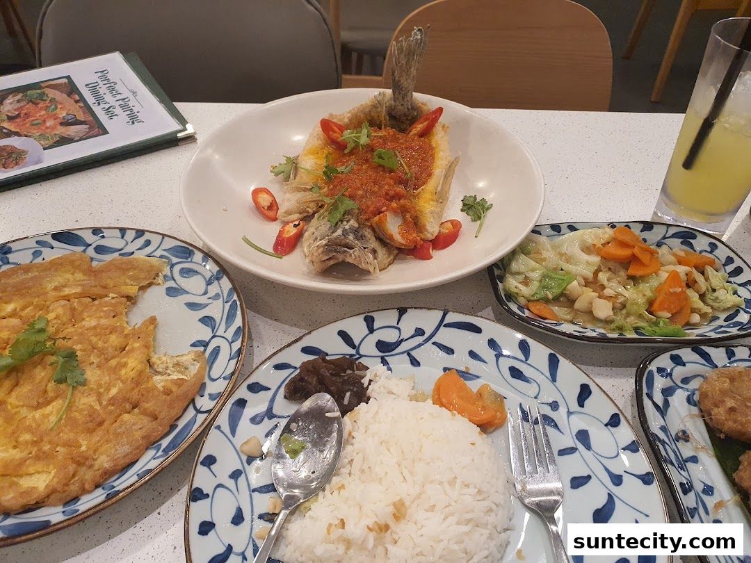 A table laden with Indonesian dishes including fried fish, omelette, vegetables, and rice.
