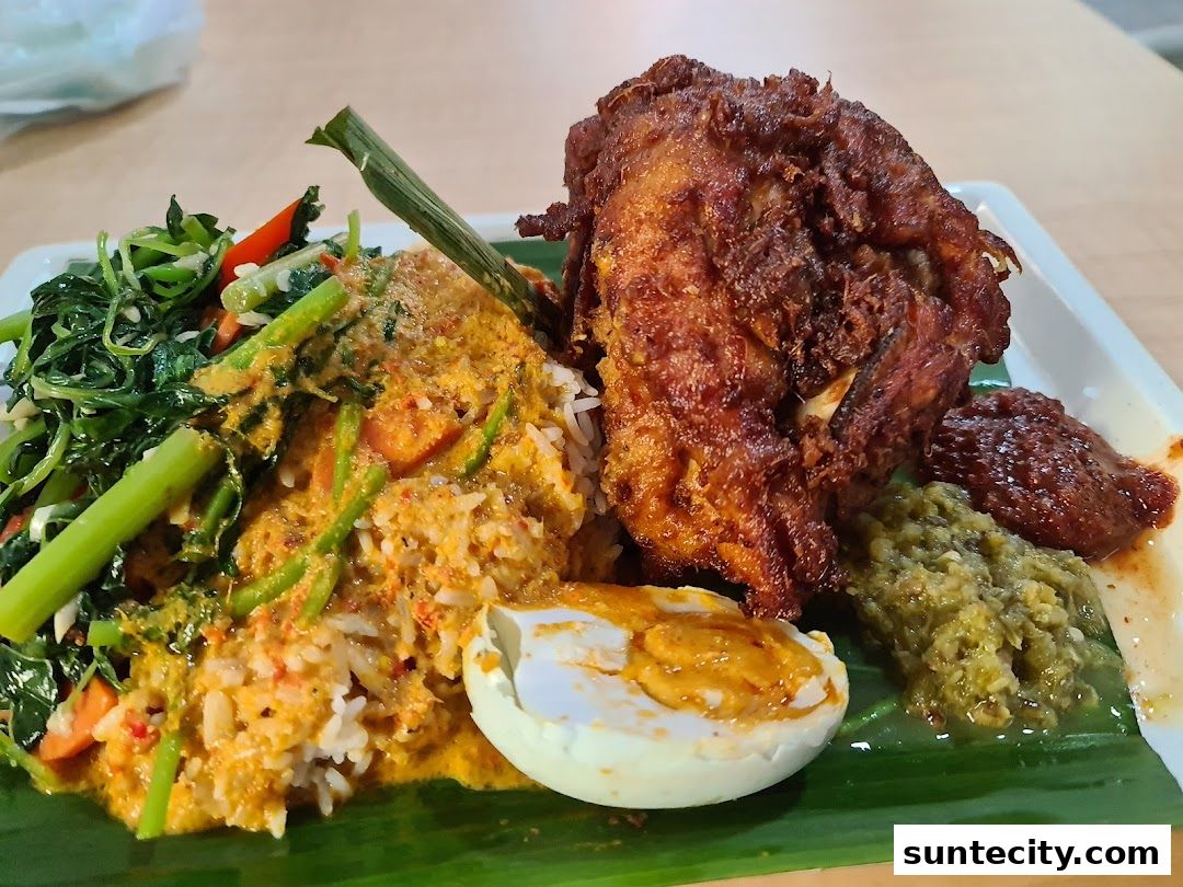 A plate of Indonesian Padang cuisine featuring fried chicken, rice, vegetables, and egg.