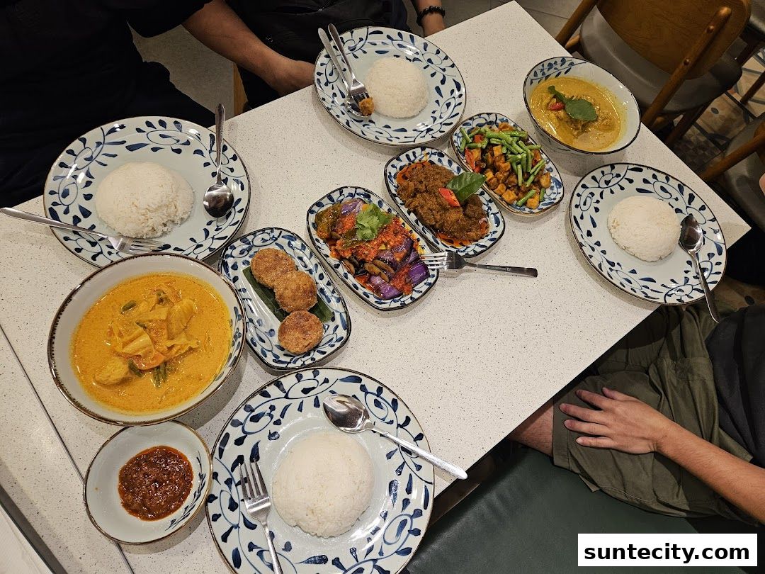 A table laden with various Indonesian dishes, including rice, curry, and stir-fried vegetables.