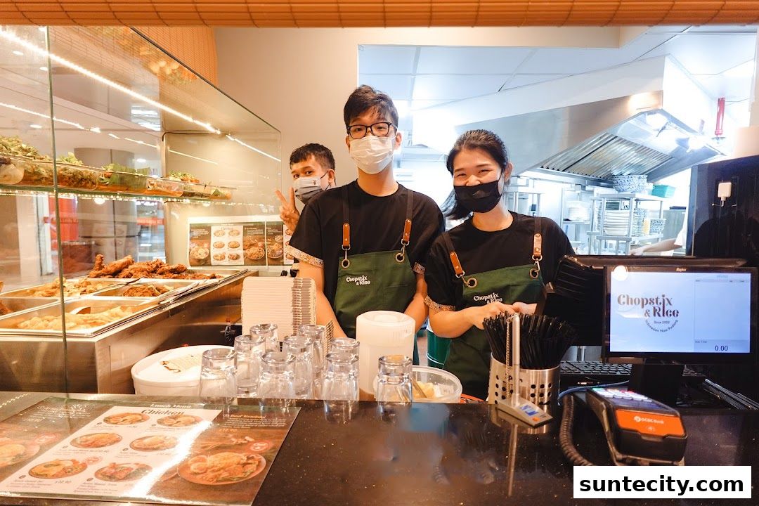 Staff at Chopstix & Rice Indonesian Restaurant smiling behind the counter with food displayed.