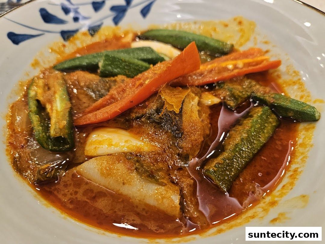A close-up of a delicious Indonesian dish with fish, okra, and chili in a rich curry sauce.
