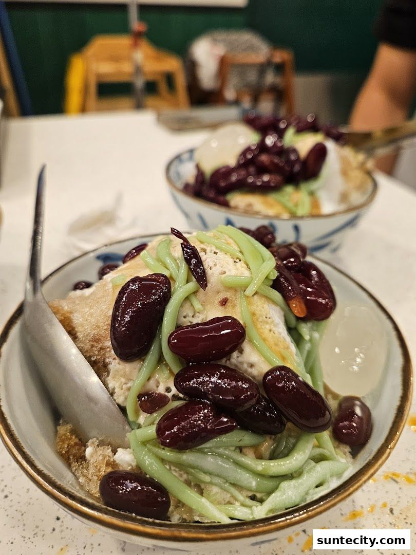 Close-up of two bowls of Indonesian dessert with shaved ice, red beans, and green jelly.