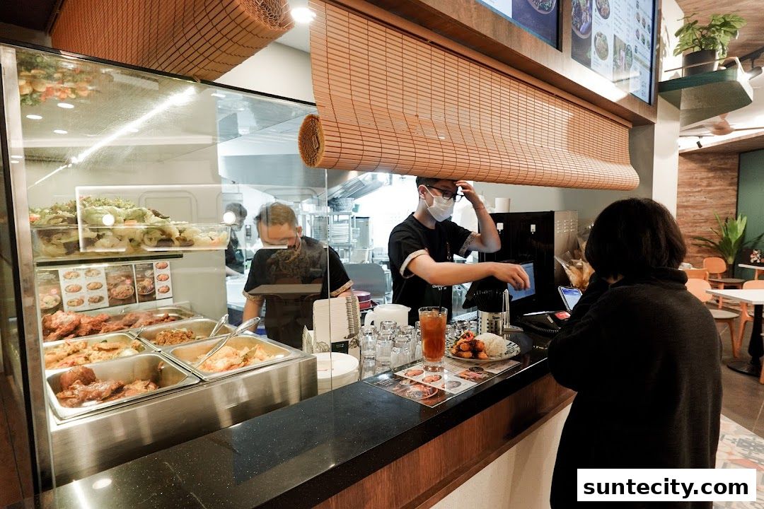 Staff serving food at a counter in an Indonesian restaurant with display of various dishes.