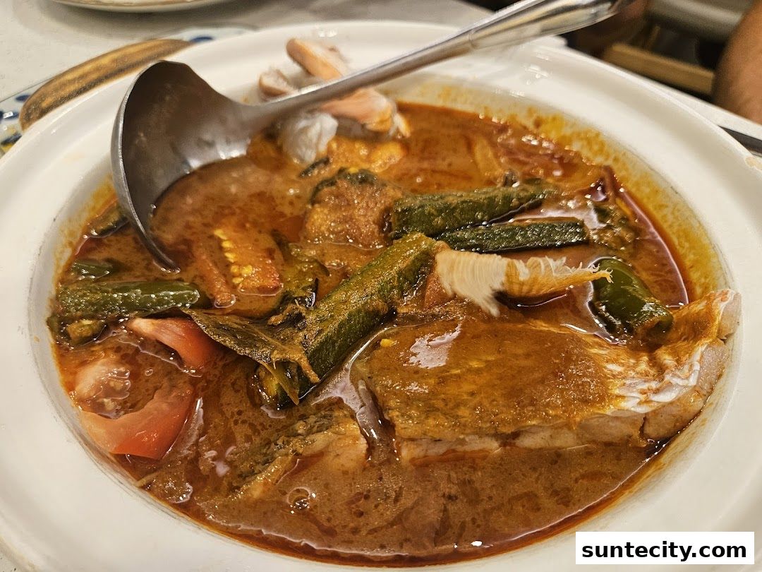 A close-up shot of a delicious Indonesian curry dish with fish, okra, and tomatoes.