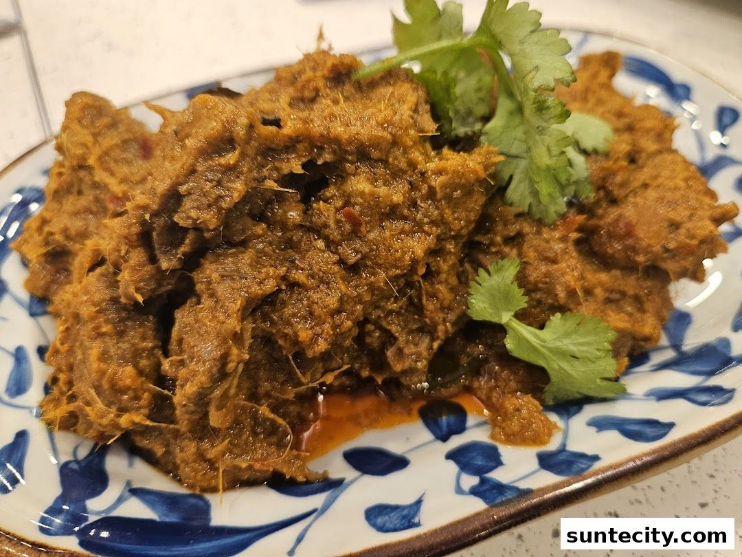 A close-up shot of a flavorful Indonesian beef rendang dish garnished with fresh cilantro.