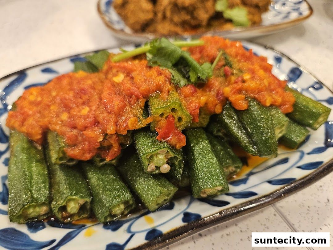A plate of okra topped with a spicy red chili sauce and garnished with cilantro.