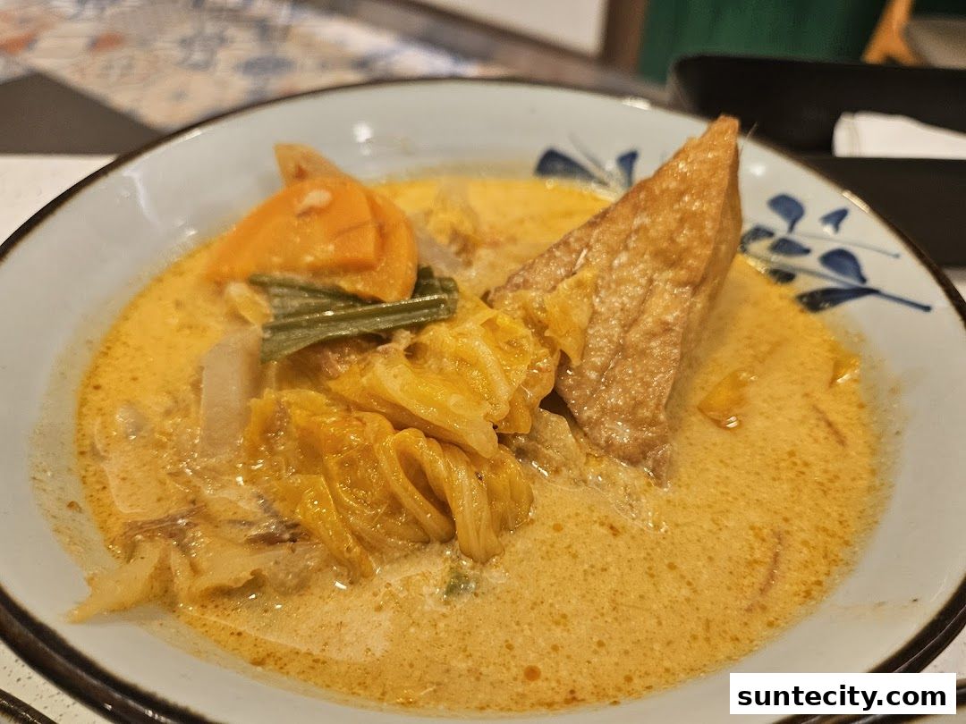 A close-up of a delicious Indonesian curry dish with tofu, vegetables, and a rich, creamy sauce.