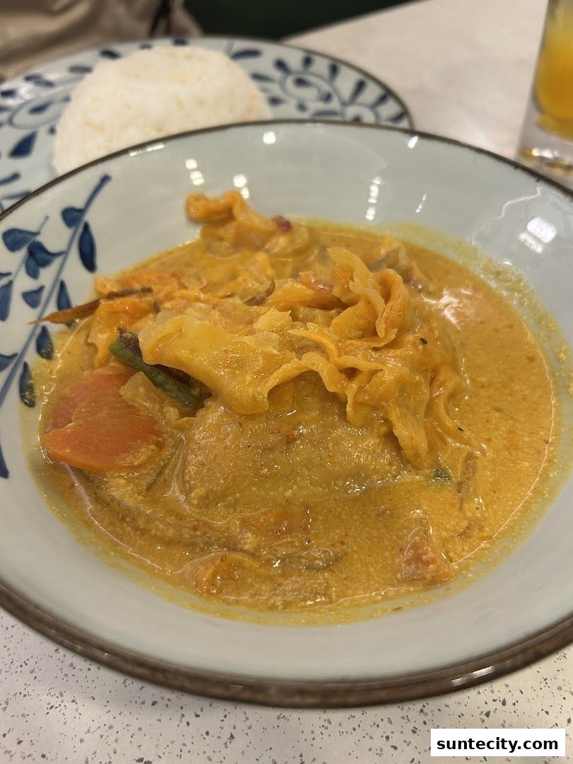 A close-up of a delicious Indonesian curry dish with rice in a decorative bowl.