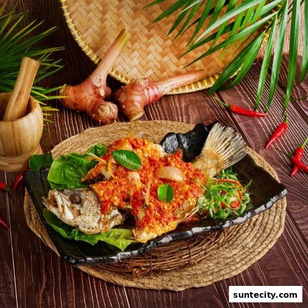 A whole fried fish topped with a vibrant red chili sauce and garnished with herbs.