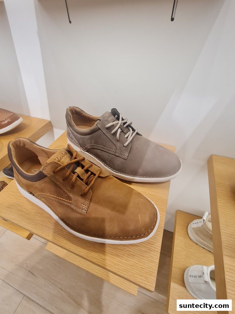 A display of men's casual shoes from Clarks on wooden shelves.