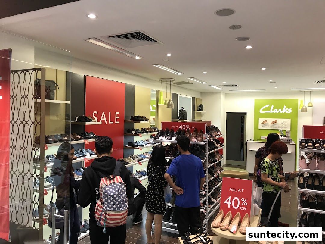 Customers browse shoes in a brightly lit Clarks store with a large 'SALE' sign and 40% off promotion.