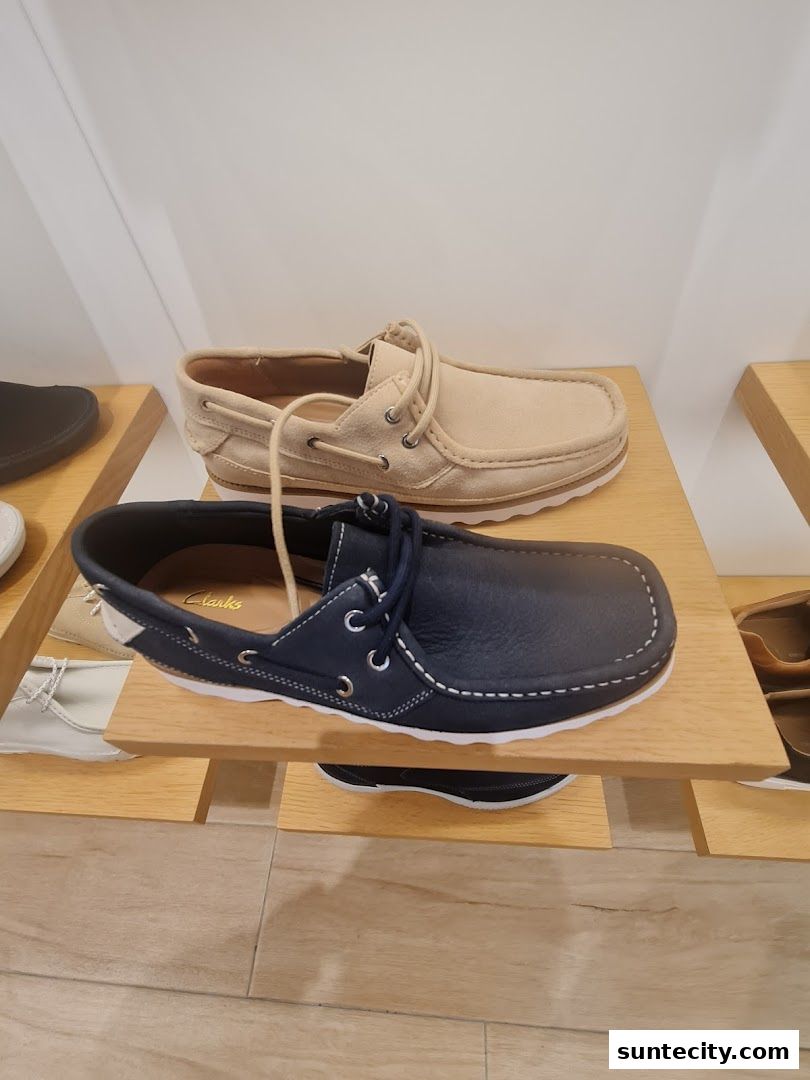 A display of Clarks shoes, featuring a beige and a navy blue loafer style shoe.