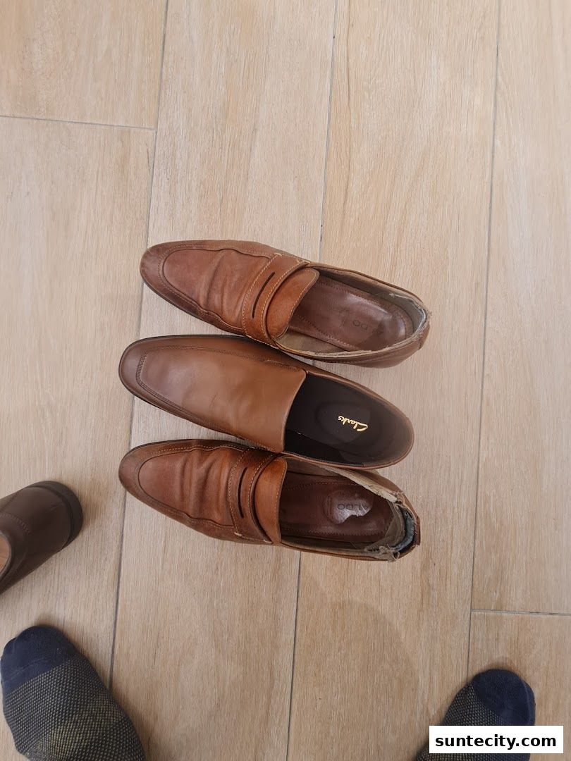 A top-down view of three brown leather loafers on a light wooden floor.