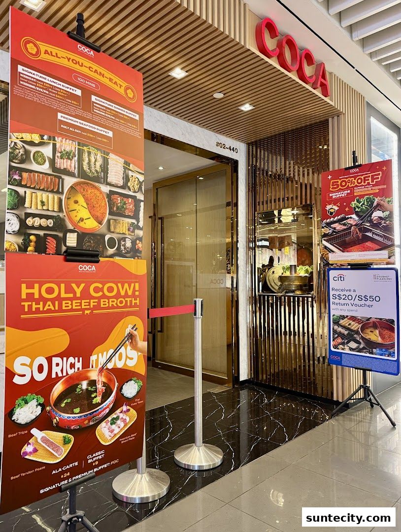 The entrance of COCA restaurant with promotional banners displaying buffet offers and Thai beef broth.