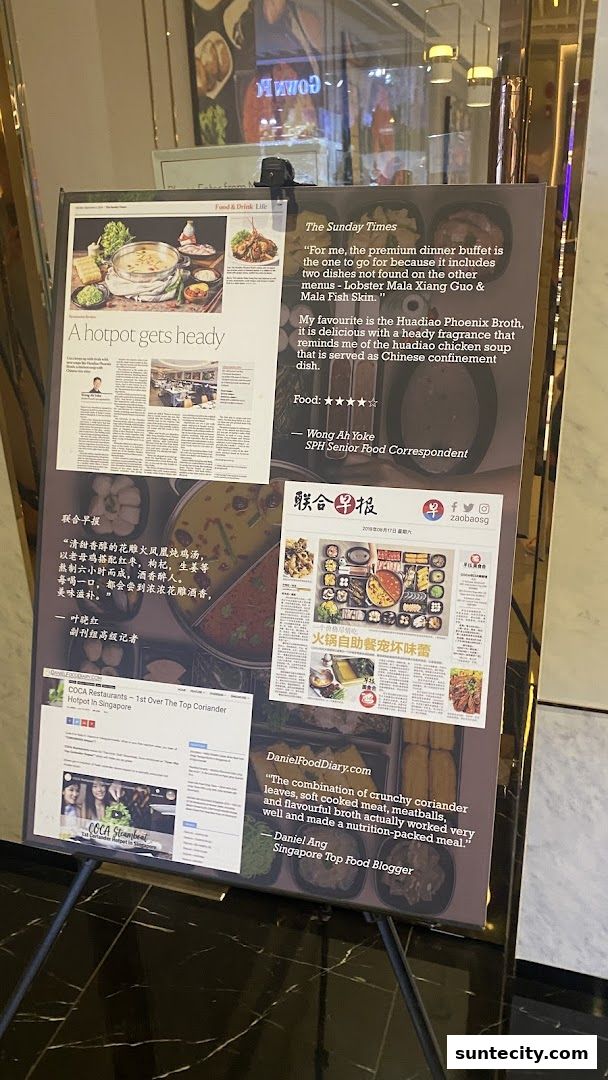 A display board showcasing newspaper and blog reviews of COCA Restaurants' hotpot.
