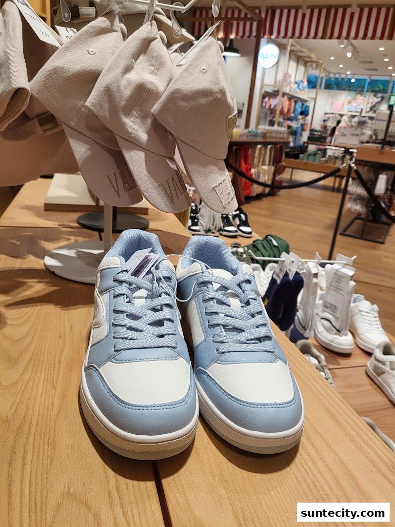 A display of stylish blue and white sneakers and casual caps inside a retail store.