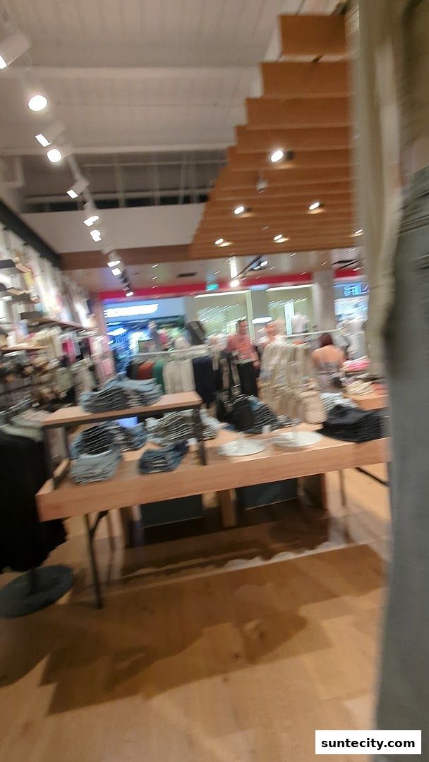 Interior view of a Cotton On store with clothing displays and shoppers.