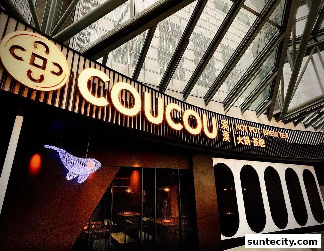 The illuminated sign of Coucou Hotpot Brew Tea with a decorative whale sculpture.