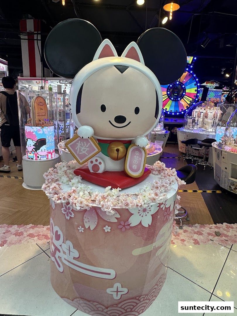 A large character statue decorated with cherry blossoms in an arcade.