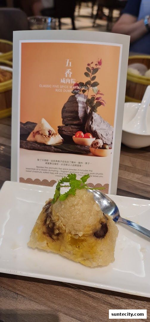 A close-up of a classic five spice marinated pork rice dumpling on a white plate.