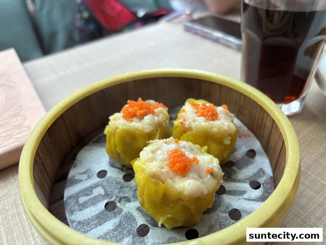 A close-up of three delicious dim sum dumplings topped with orange roe in a bamboo steamer.