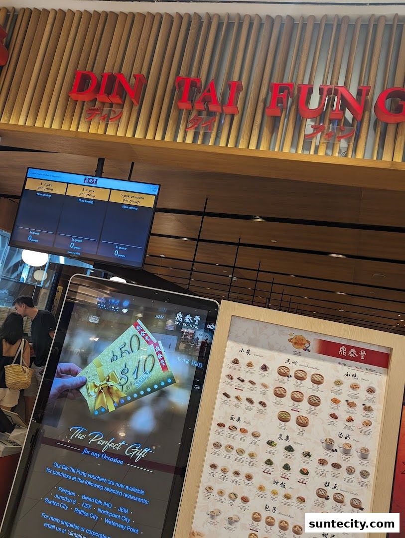 Din Tai Fung restaurant signage with a queue display and a digital advertisement for gift vouchers.