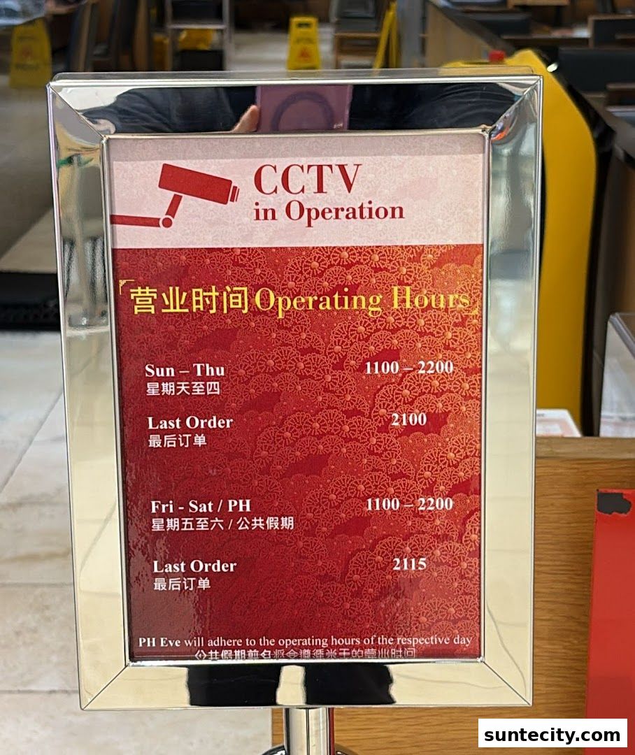 A sign displaying operating hours and CCTV in operation for Din Tai Fung.