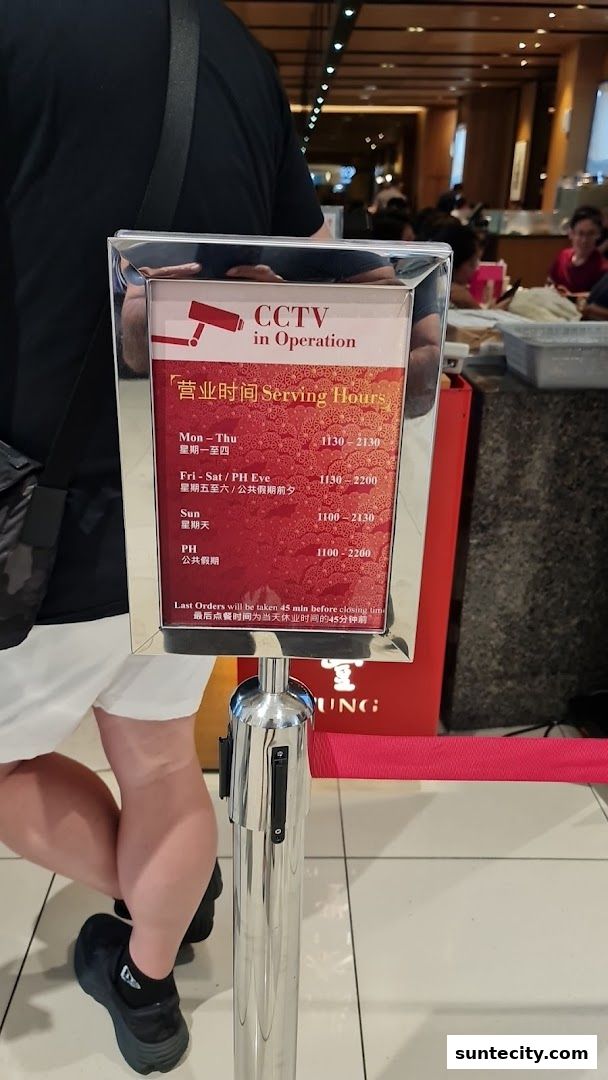 A sign displaying serving hours and CCTV operation at Din Tai Fung.