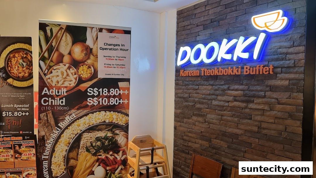 The Dookki Korean Tteokbokki Buffet restaurant entrance with a large promotional poster and neon signage.