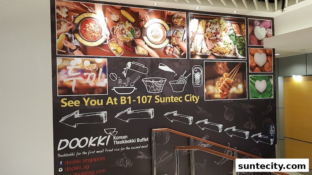 A wall advertisement for Dookki Korean Tteokbokki Buffet, showing food images and directions.