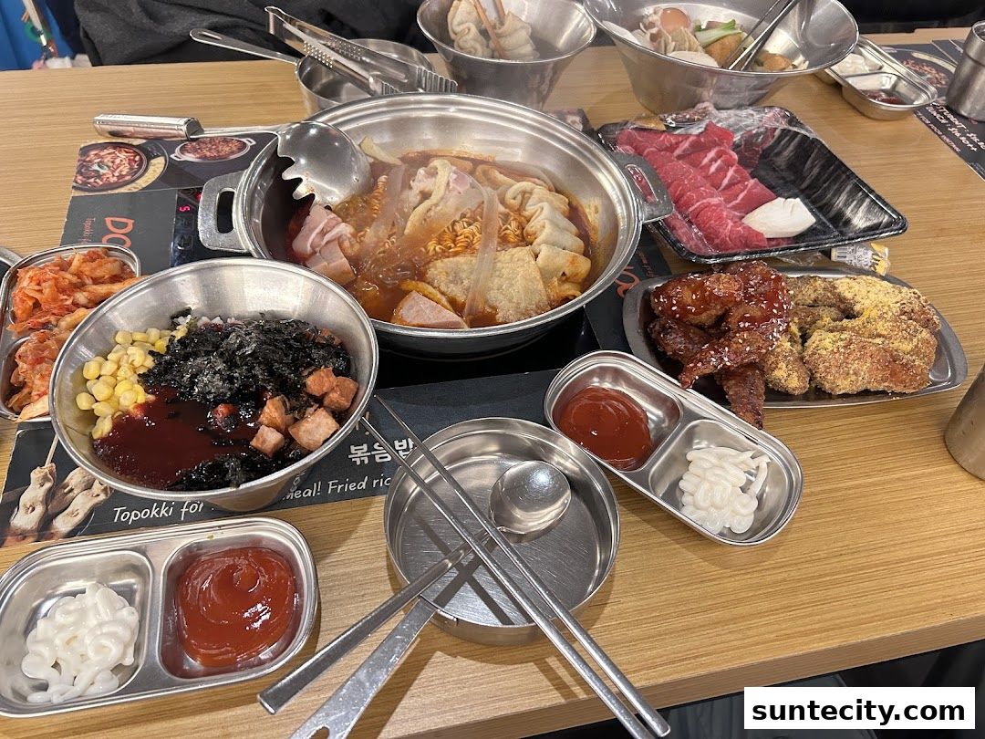 A table filled with various Korean dishes including tteokbokki, fried chicken, and beef.