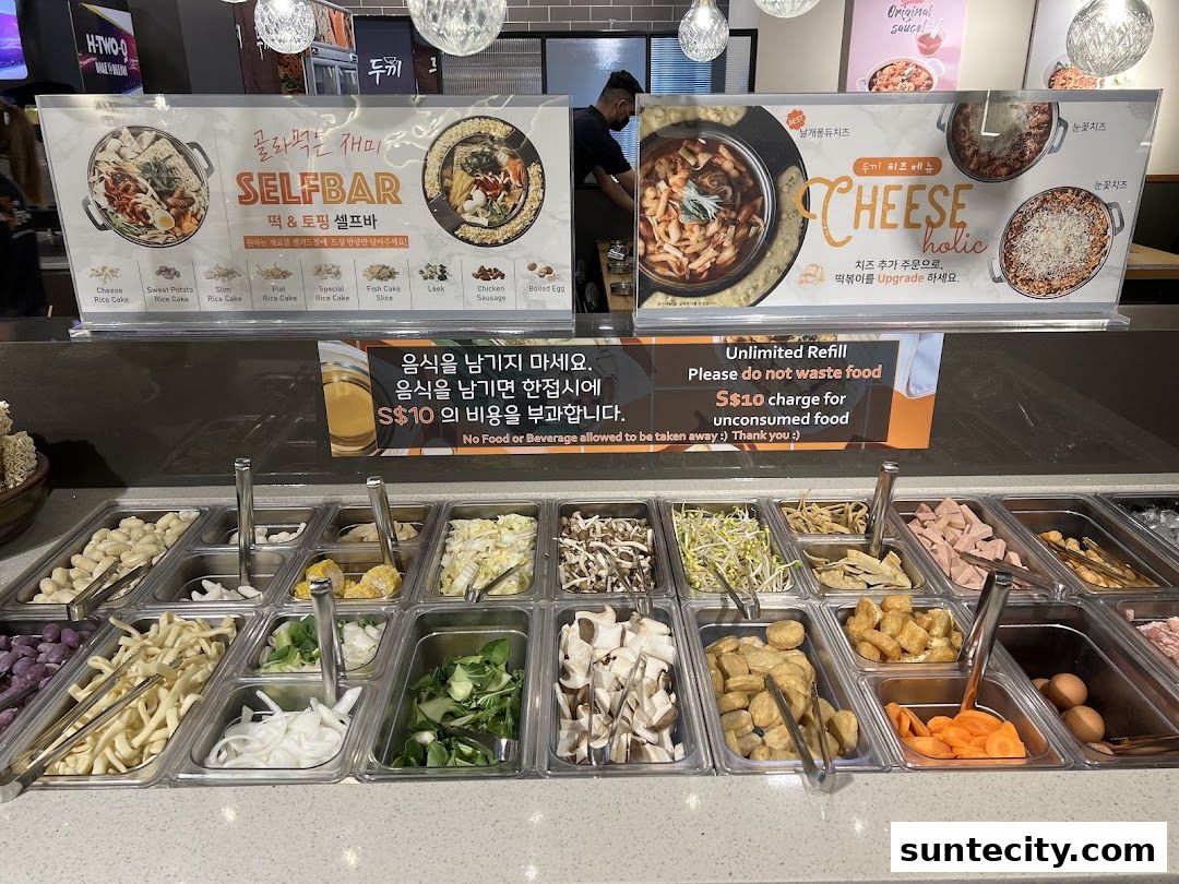 A self-serve bar with various ingredients for Korean tteokbokki and cheese dishes.