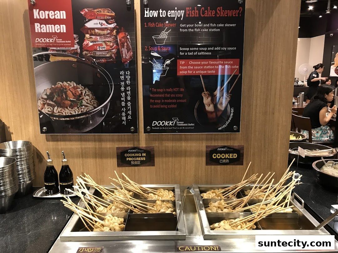 A display of Korean ramen and fish cake skewers at Dookki, with cooking status indicators.