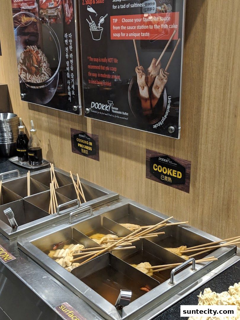 A display of Korean Tteokbokki buffet with various fish cakes cooking in broth.