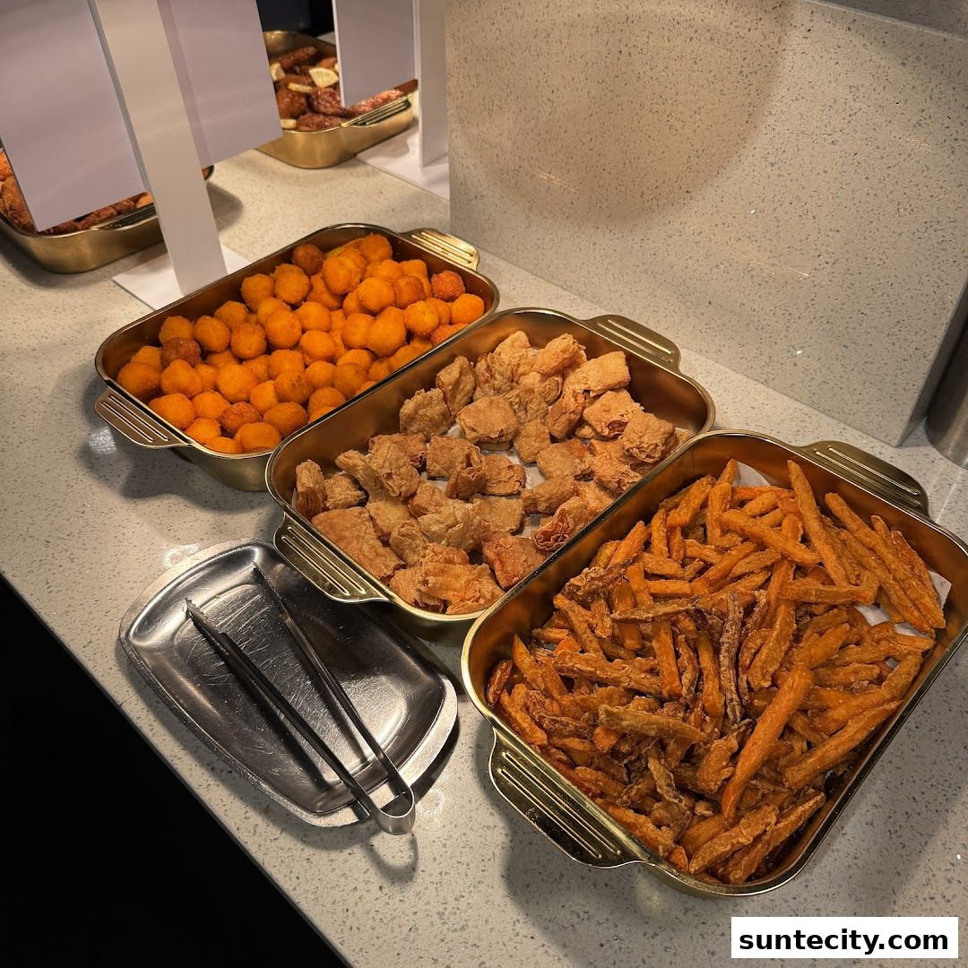 Three trays of fried food, including orange balls, fried chicken pieces, and sweet potato fries.