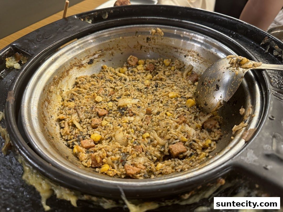 A close-up of a savory fried rice dish with corn and meat in a pot.