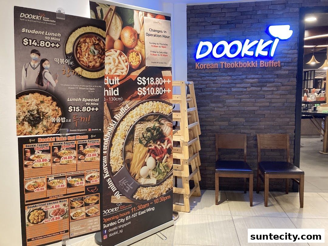 The entrance of Dookki, a Korean Tteokbokki Buffet restaurant, with promotional posters and seating.
