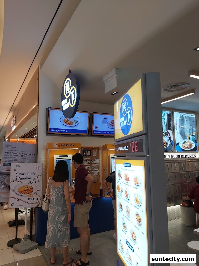 People ordering food at a self-service kiosk with digital menus and food displays.