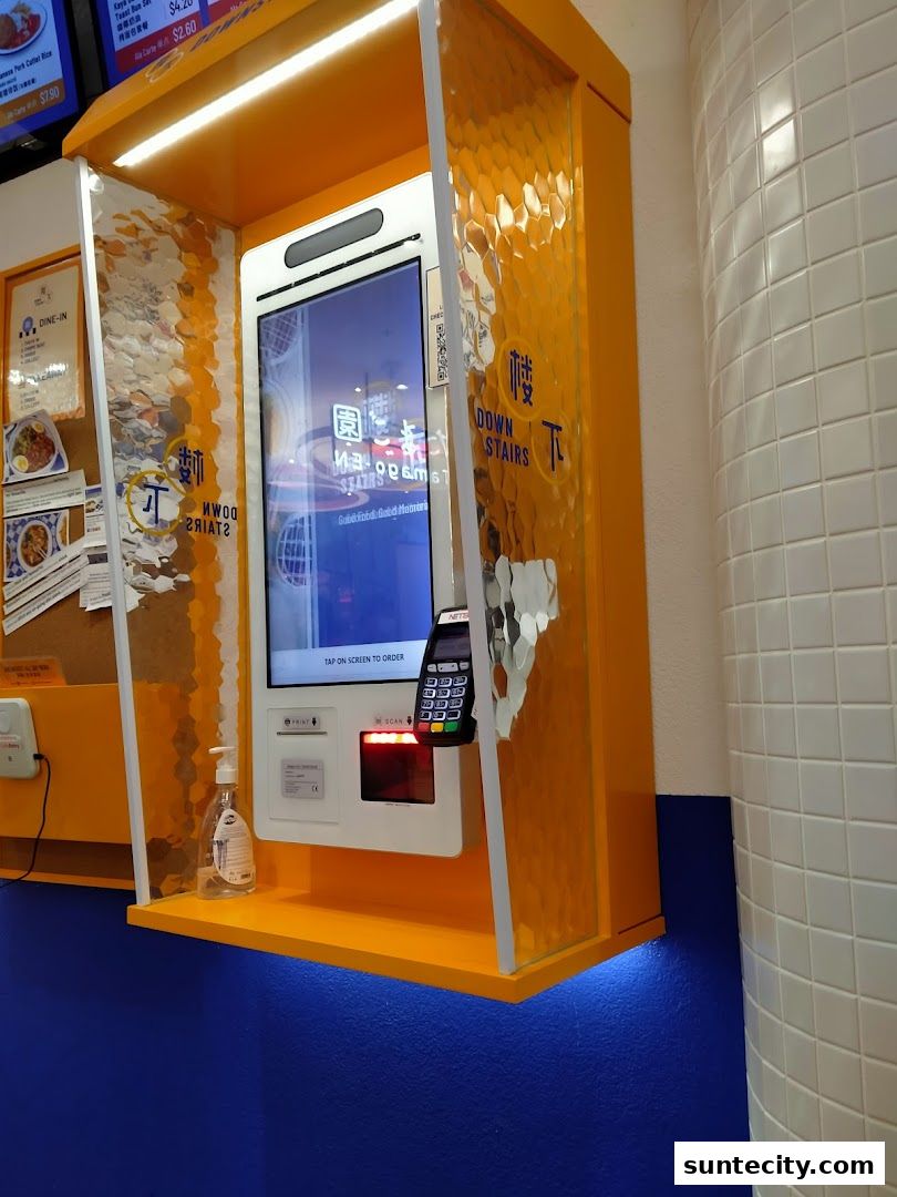 A self-order kiosk with a touchscreen, card reader, and hand sanitizer.