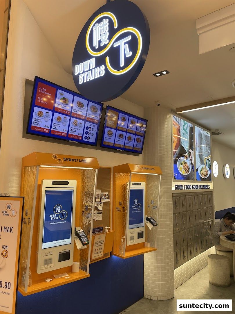 A food establishment with digital menus, self-order kiosks, and a sign reading 'Downstairs'.