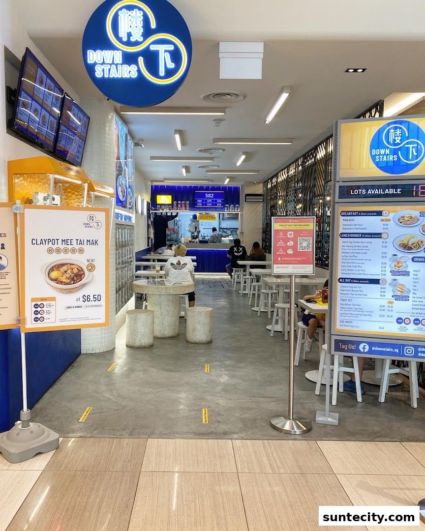 The entrance of a modern food establishment with seating and a prominent sign.