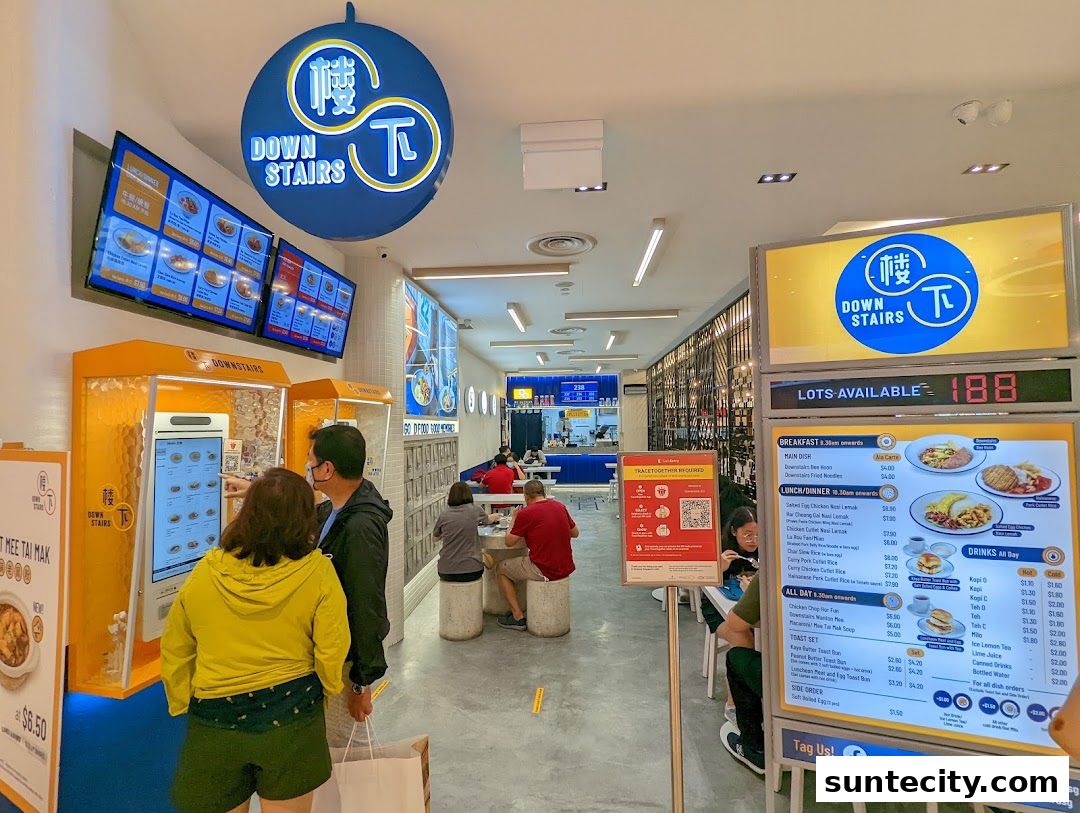 People ordering food at Downstairs restaurant with digital menus and a display showing available lots.