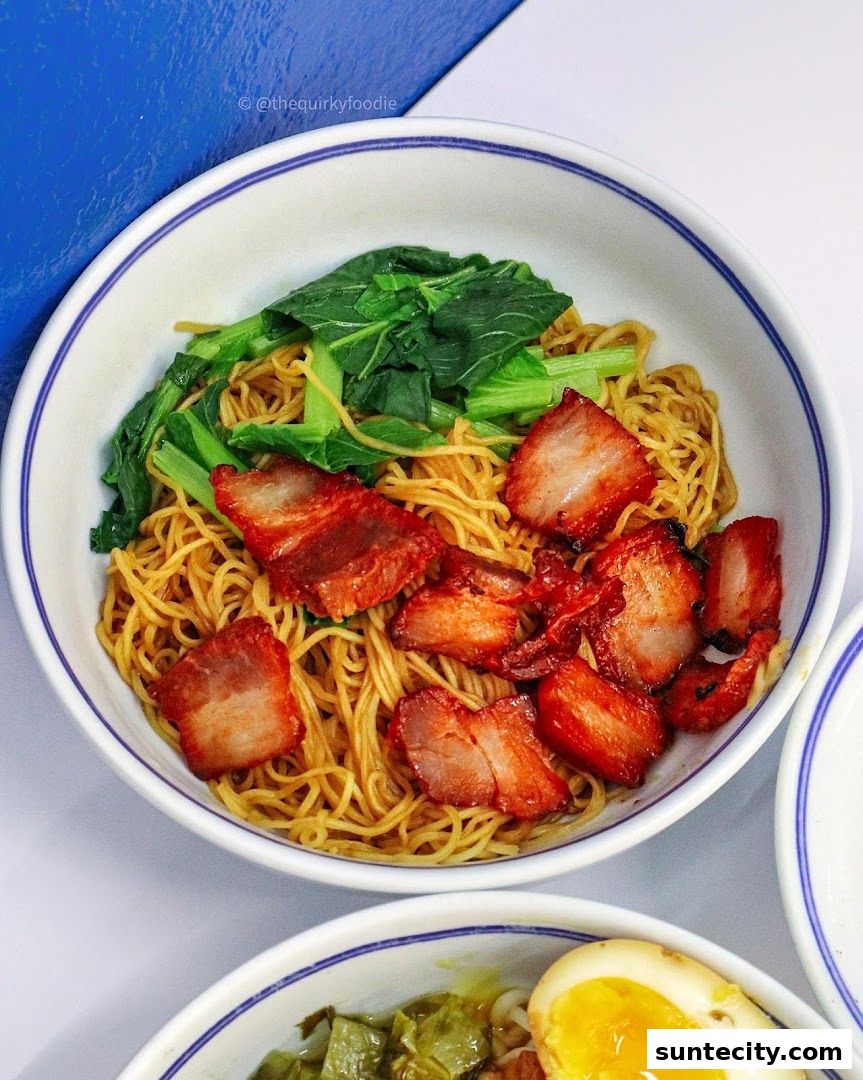 A close-up shot of a bowl of noodles topped with char siu pork and green vegetables.