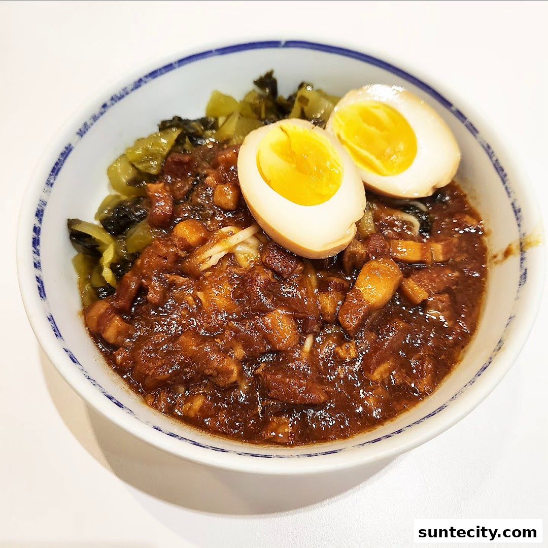A bowl of braised pork rice with braised eggs and pickled vegetables.