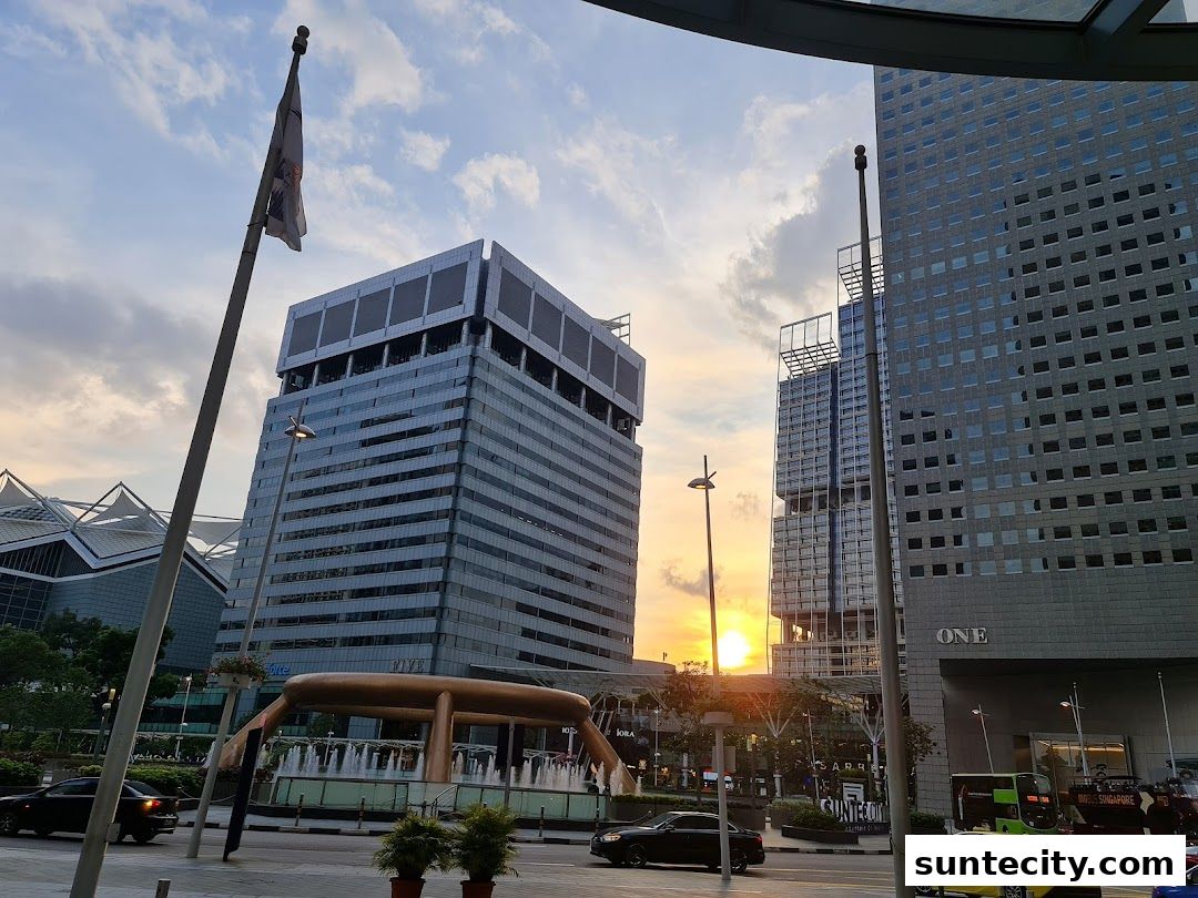 Cityscape with modern buildings and a fountain at sunset.