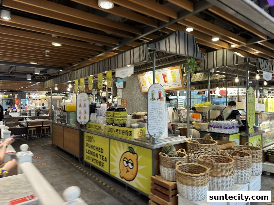 A food stall in a mall featuring drinks and baskets of fruit.