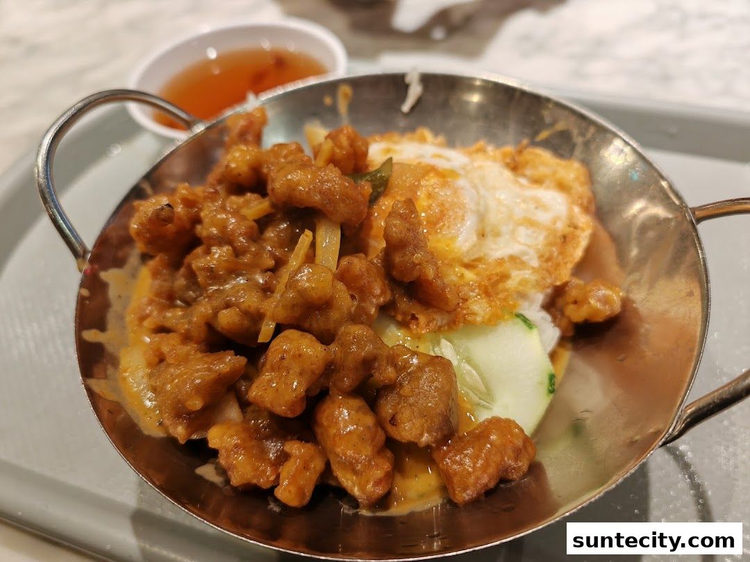 A close-up of a delicious meal with fried chicken, a fried egg, rice, and cucumber.