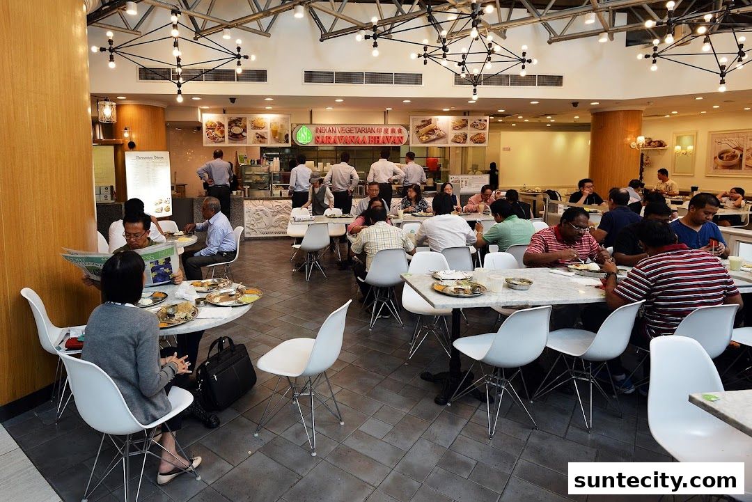A busy food court with many people dining at tables, featuring an Indian vegetarian restaurant.