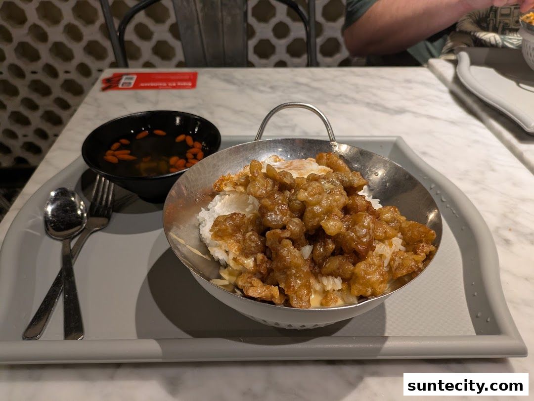 A close-up of a delicious meal served on a tray, featuring rice with crispy toppings and a side of soup.
