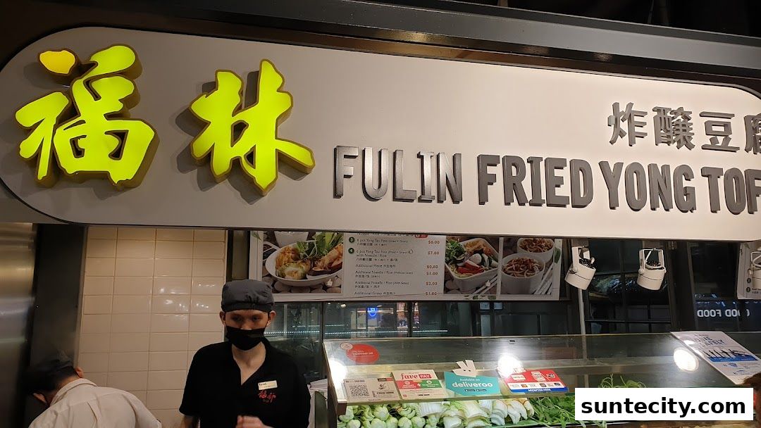 A food stall with a sign for FULIN FRIED YONG TOFU and a display of fresh ingredients.